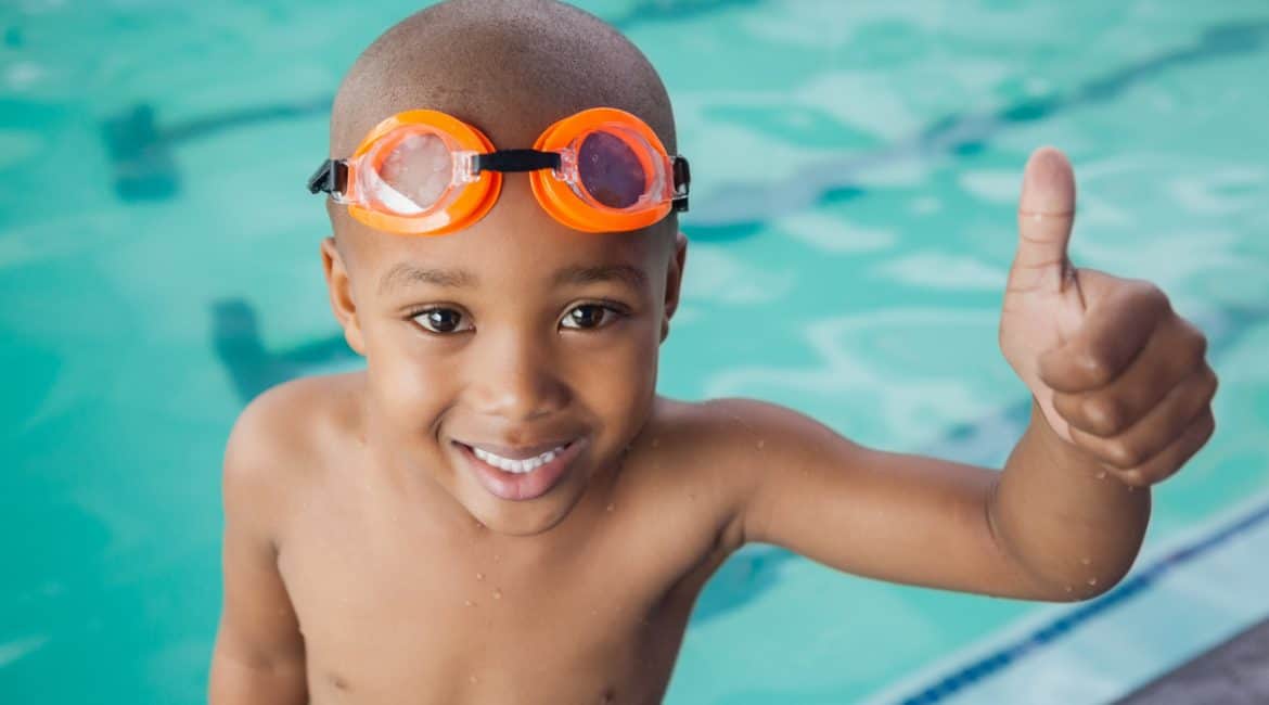 Cute little boy giving thumbs up at the pool